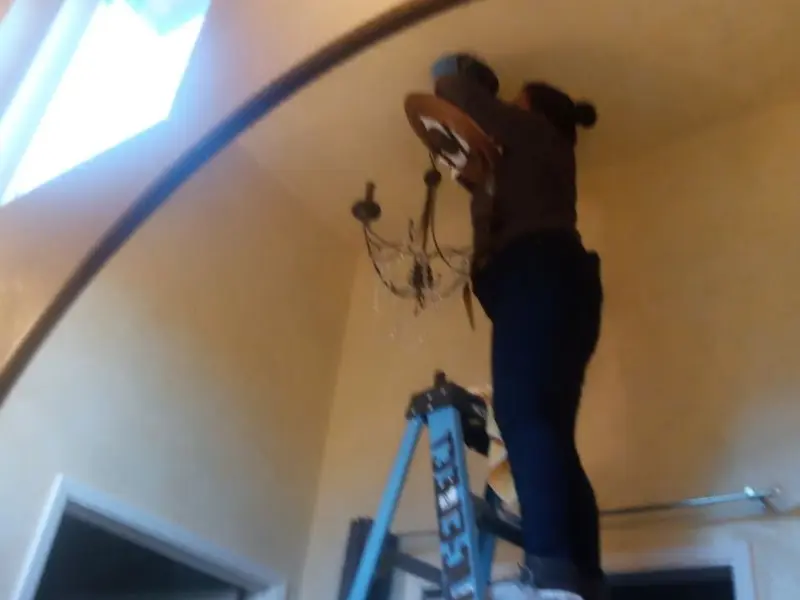 Electrician installing a chandelier in a Dripping Springs residence